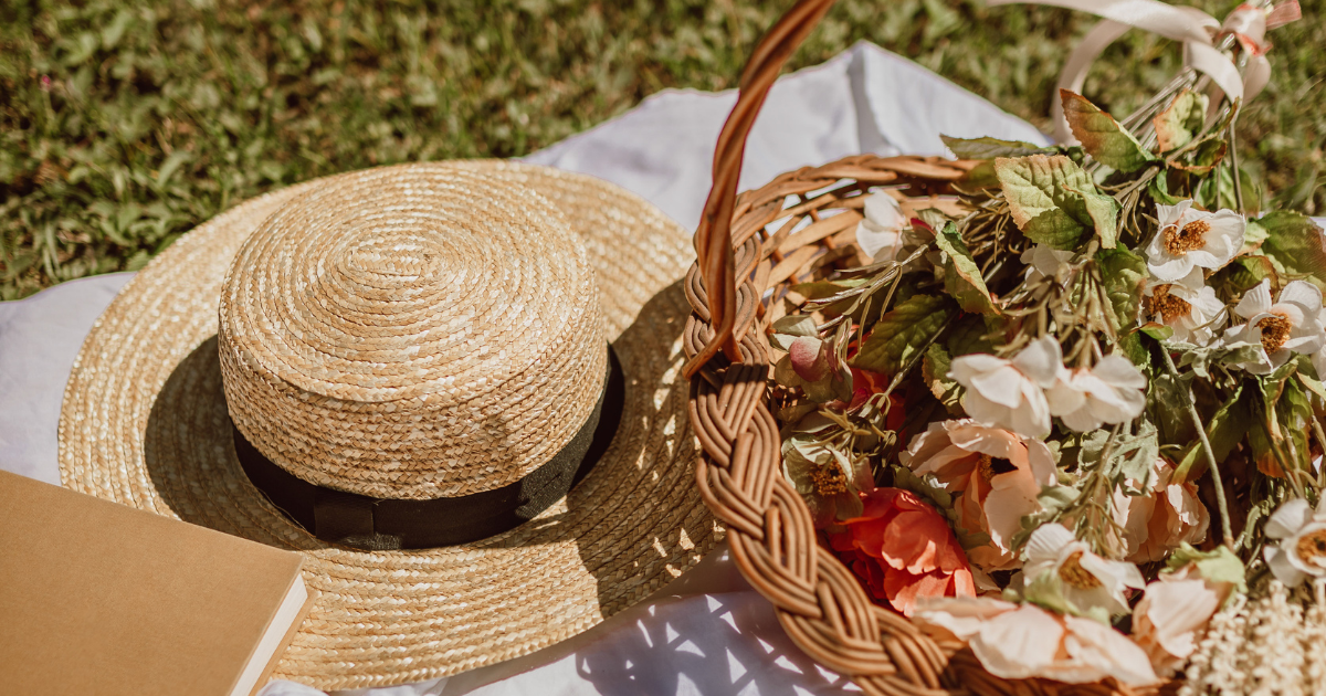 A picnic basket filled with vibrant flowers and an open book resting beside it,